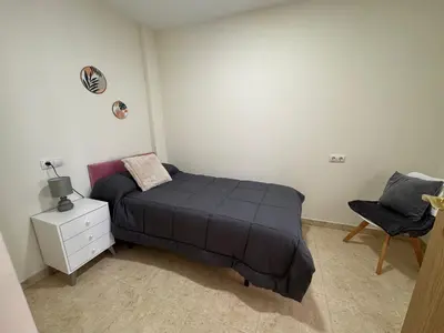 a small bedroom with a bed and a chair at Casa Alan in Burriana