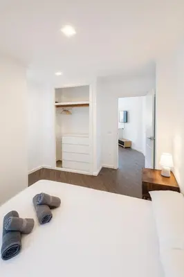 a bedroom with a white bed with two pairs of slippers at Apartment Market Ruzafa 10B in Valencia