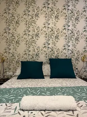 a bed with two blue pillows and a floral wallpaper at Estupendo apartamento en Llíria in Lliria