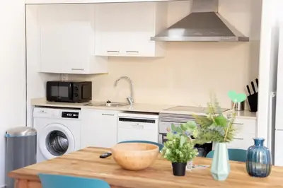 a kitchen with white cabinets and a wooden table at VLC Host - Cuber Apartments in Valencia