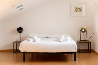 a white bed in a room with two lamps at VLC Host - Cuber Apartments in Valencia