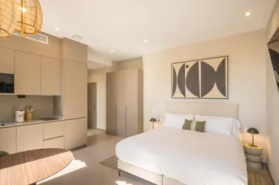 a bedroom with a white bed and a kitchen at Housing Maritim by SharingCo in Valencia