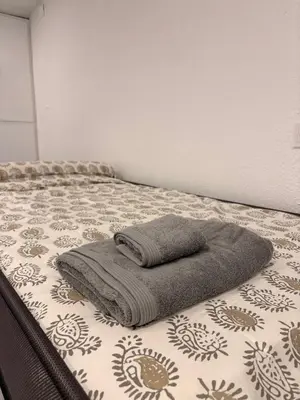 a bed with a blanket and a towel on it at LITTLE Hostel in Puerto de Sagunto