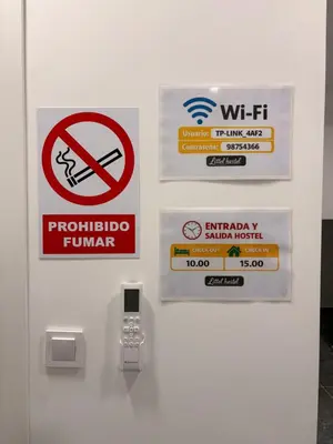 a door with signs on it with a cell phone at LITTLE Hostel in Puerto de Sagunto