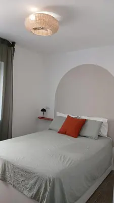 a bedroom with a white bed and a light fixture at El Faro de Nules in Mascarell