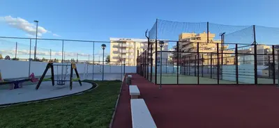 a batting cage with a playground with buildings in the background at Apartamento Timia OASIS in Canet de Berenguer