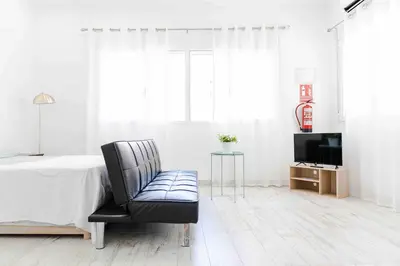 a bedroom with a bed and a chair and a television at Boutique Loft 1 next to Torres de Serrano in Valencia
