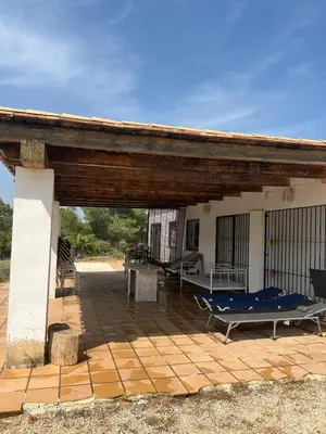 a covered patio with a hammock on a house at Chalet en la naturaleza in Macastre