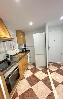 a kitchen with a white refrigerator and a tile floor at De frente al mar in Sueca