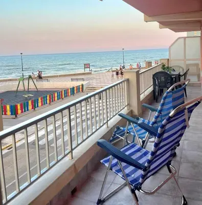 two blue chairs sitting on a balcony overlooking the beach at De frente al mar in Sueca