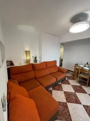 a living room with an orange couch and a table at De frente al mar in Sueca
