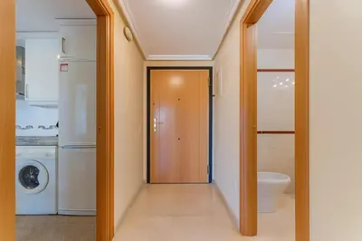 a hallway leading to a laundry room with a door at Tu refugio moderno en Valencia - piscina, gimnasio y padel incluidos in Valencia