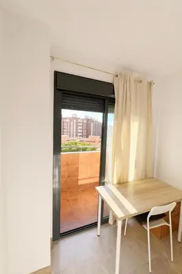 a table and a chair in a room with a window at Cortes Suite - Pool paddle tennis court and gym in Valencia