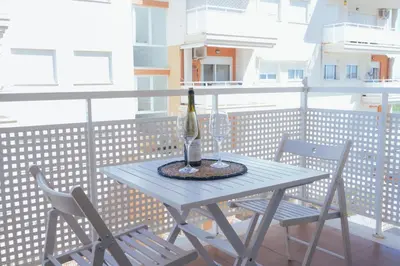 a table and chairs on a balcony with a bottle of wine at Blanca Mar in Barrio-Mar