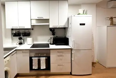 a kitchen with white cabinets and a refrigerator at Apartmento en 5 Mares in Puebla de Farnals