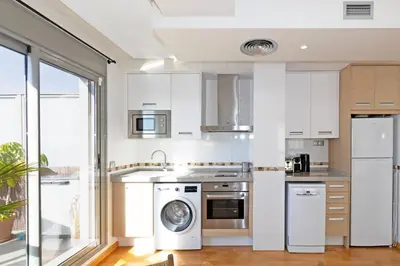 a kitchen with white cabinets and a washer and dryer at GuestReady – Modern Flat with Terrace in Valencia in Valencia