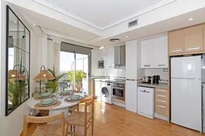 a kitchen with white cabinets and a table and chairs at GuestReady – Modern Flat with Terrace in Valencia in Valencia