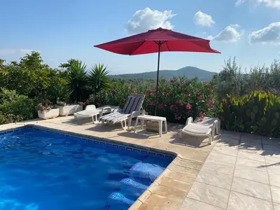 a pool with two chairs and a red umbrella at Casita Ramona in Valencia