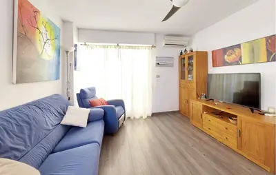 a living room with a blue couch and a television at Stunning Apartment In Moncofa With Swimming Pool in Moncófar