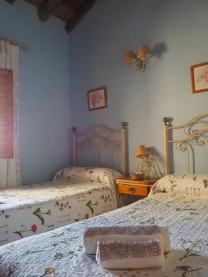 a bedroom with two beds and a table and a window at La Ontina Alojamientos Rurales in Abejuela