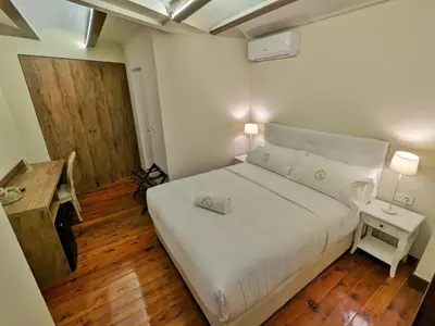 a bedroom with a white bed and a wooden floor at Hotel Catalina Suites in Valencia