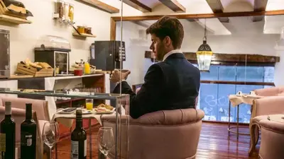 a man sitting in a chair at a table with wine bottles at Hotel Catalina Suites in Valencia