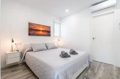 a white bedroom with a bed with two towels on it at Duplex-Port-Valencia 14 in Valencia