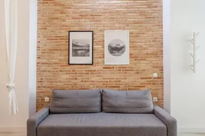 a couch in front of a brick wall with two pictures at New Flat center historic Ruzafa Wifi AC in Valencia