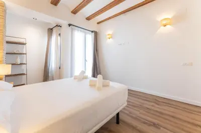 a white bedroom with a white bed and a window at Yturralde by Alma Suites in Valencia