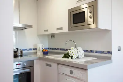 a white kitchen with a sink and a microwave at SingularStays Oceanic in Valencia