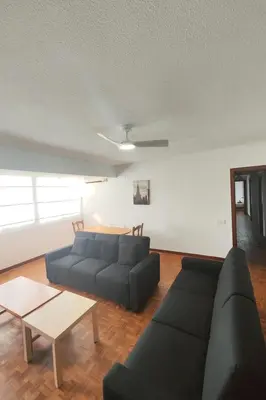 a living room with a black couch and a table at Apartamento Familiar En Nuevo Centro - Parque Central Turia in Valencia