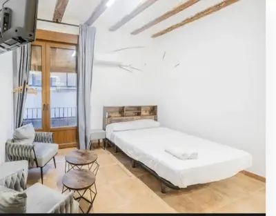 a bedroom with two beds and a couch and chairs at Suite centro con cocina in Valencia