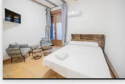 a bedroom with a large white bed and chairs at Suite centro con cocina in Valencia