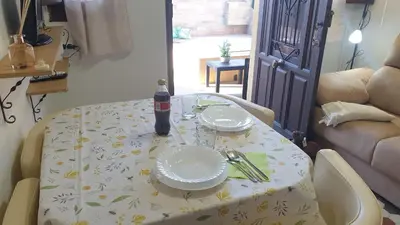 a table with a bottle of soda and plates on it at Adosado acogedor en la Cañada con piscina privada in Partida de La Cañada