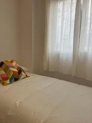 a white bed with a pillow and a window at Terraza 120 m2 y paellero - Metro & Aeropuerto in Manises
