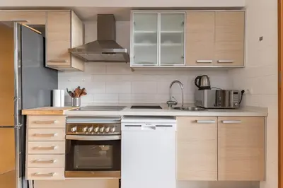 a kitchen with white appliances and wooden cabinets at Loft Doble Altura con Terraza Panorámica y Piscina in Burjasot