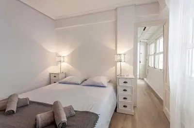 a white bedroom with a large bed and a window at Valencia Flat Rental 3 bedroom in Extramurs in Valencia