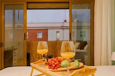 two glasses of wine and a plate of fruit on a table at Cabañal BeachFront , 1 Min to Sea , AC , Coffee , Balcony , FastWifi in Valencia