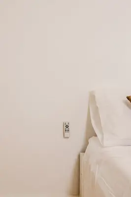 a white bedroom with a bed and an alarm clock on the wall at Cabañal BeachFront , 1 Min to Sea , AC , Coffee , Balcony , FastWifi in Valencia
