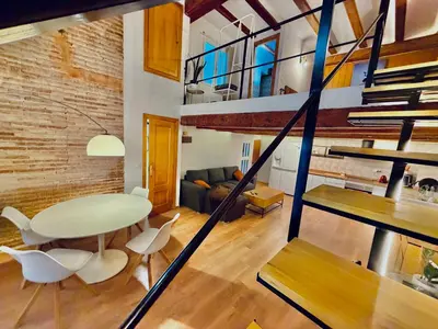a living room with a table and chairs and a staircase at Duplex en el Carmen in Valencia