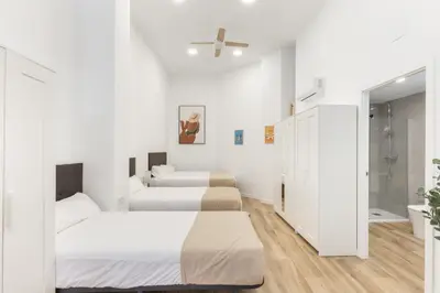 two beds in a room with white walls and wooden floors at Urban loft Benicalap in Valencia