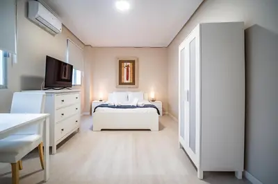 a white bedroom with a bed and a tv at Apartment Ruzafa Market 6A in Valencia