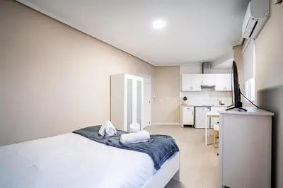 a white bedroom with a bed and a kitchen at Apartment Ruzafa Market 6A in Valencia