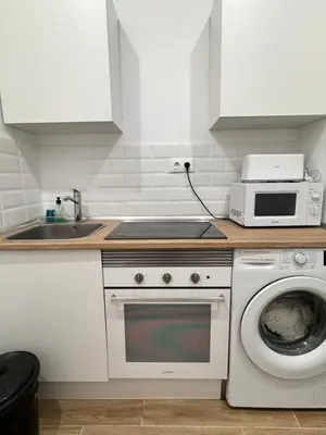 a kitchen with a washing machine and a microwave at Habitacion privada con baño privado II in Valencia