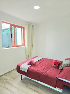a bedroom with a bed with red sheets and a window at La Casita de Beni Valencia in Valencia