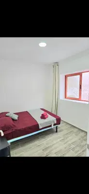 a bedroom with a bed with red sheets and a window at La Casita de Beni Valencia in Valencia