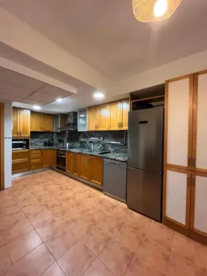 a large kitchen with wooden cabinets and stainless steel appliances at Casa familiar 3 dormitorios Jardín Piscina Barbacoa Zona de entrenamiento in Bétera