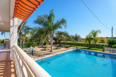 a swimming pool on the balcony of a house with palm trees at Masia Miliuca Paraíso rural a un paso de Valencia - Rural paradise close to Valencia in Bétera