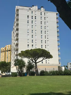a tall white building with a tree in a park at Canet al Mar Luxe y Confort-Pet Friendly in Canet de Berenguer