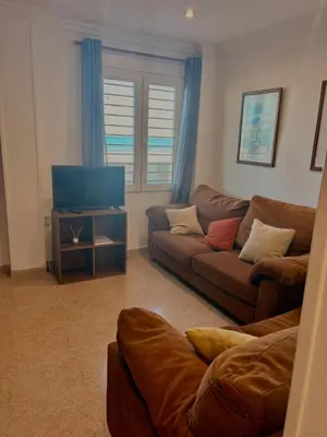 a living room with a couch and a flat screen tv at Apartamento en Primera Linea de Playa en Mareny de Barraquetes-Vistas al Mar-El Refugio del Mediterráneo in Mareny Barraquetas
